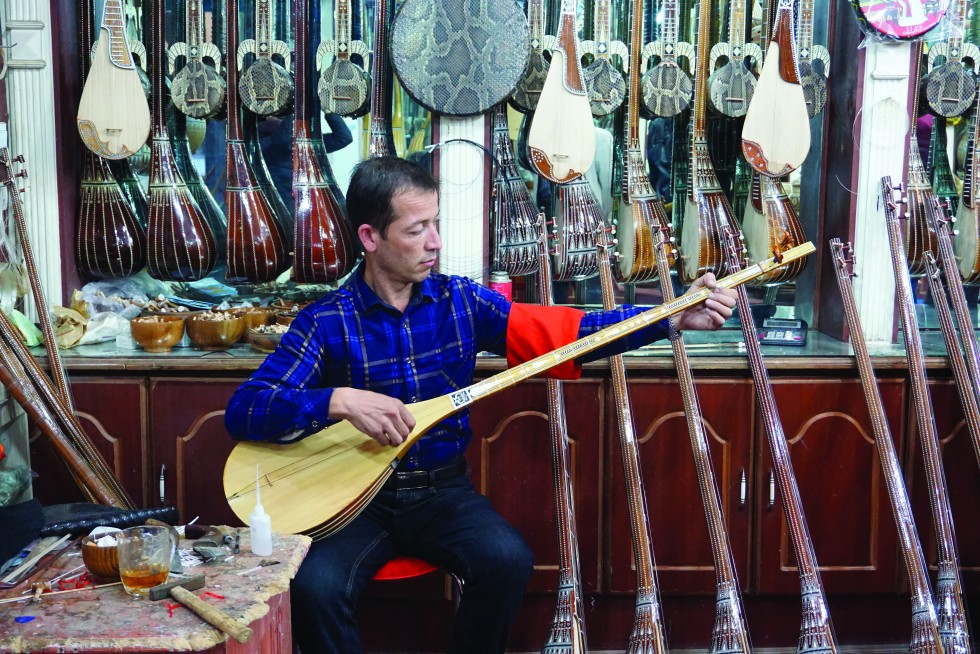 An instrument maker tunes a dutar, a long-necked lute with two strings; long ago, before the introduction of silk, the strings were made from goat intestines.