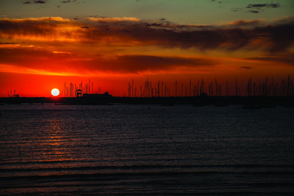 St Kilda, Australia: Sun trails as eyelid— skin of dusk falling to night past grey lunar sea.