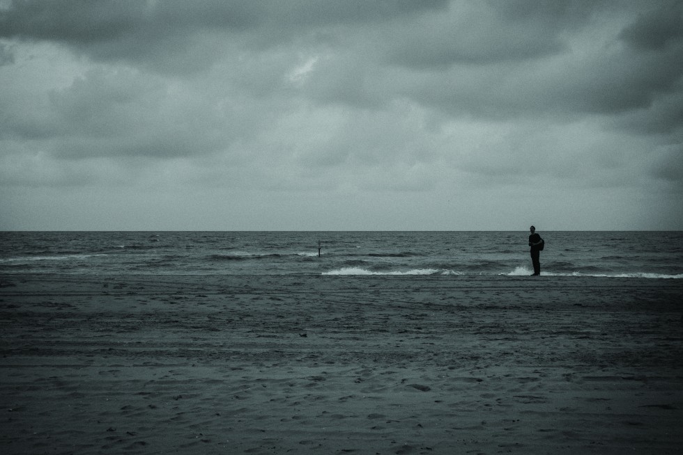 Scheveningen, Netherlands: Clouds slide down the sea to see who’s there—finding me uniformed in sand.