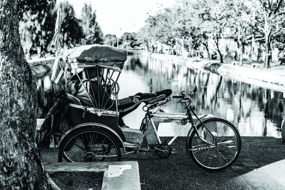 A chedi over the centuries becoming absorbed by the nature around it. A samlor driver taking a break along the city moat.