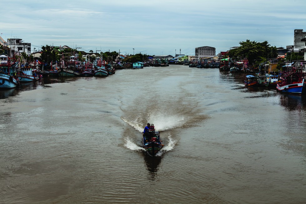 The fishing fleet is grounded by rough seas, but there is still life on the Pattani River.